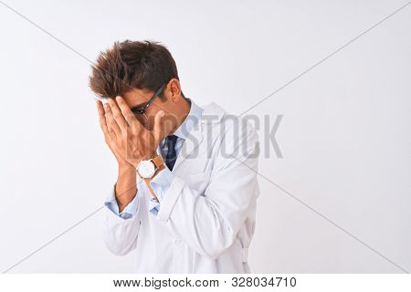 Young handsome sciencist man wearing glasses and coat over isolated white background with sad expression covering face with hands while crying. Depression concept.