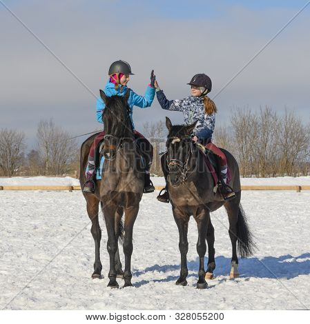 Two Caucasian Female Teenager, 13 Years Old, Are Astride Their Horses And Getting High-five Each Oth