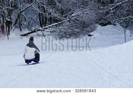 Young Woman Sledding On A Sled By A Toboggan Run. Torfhaus Resort In Harz Mountains National Park, G