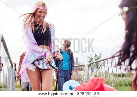 Friends Pulling Trolley As They Arrive At Music Festival Carrying Camping Equipment Onto Site