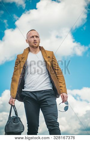 Confident Attractive Man Waiting For His Transport Wearing A White T-shirt, Brown Jacket, And Comfor