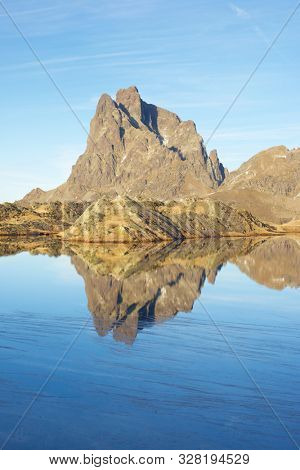 Midi Dossau Peak reflected in a lake. Ossau Valley, Pyrenees National Park, Pyrenees, France.