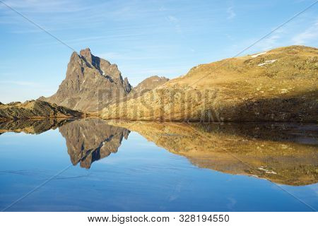 Midi Dossau Peak reflected in a lake. Ossau Valley, Pyrenees National Park, Pyrenees, France.