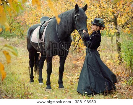 Horsewoman Girl In A Black Dress Leads A Black Horse