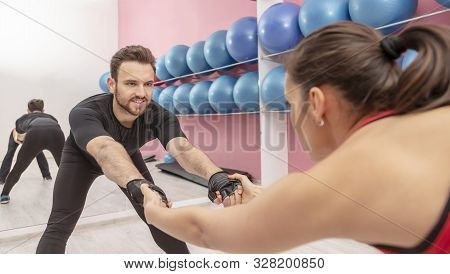 Portrait Of A Handsome Young Man Doing Stretching Exrcises In A Gym Together With His Girlfriend.
