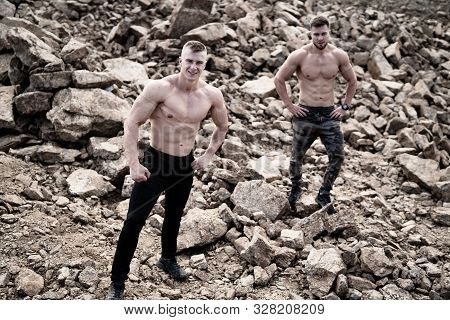 Two Fitness Strongmen Having Workout Outdoor In A Rocky Background. Bodybuilders Concept Background 