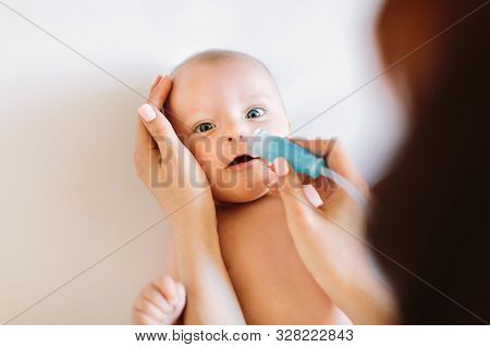 Mom Holding Her Head To A Small Girl With Her Hands Sucks The Snot From The Babys Nose Lying On The 