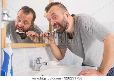 Man Brushing His Teeth In Bathroom