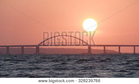 Stunning View Of The Beautiful Sunset Over The Big River And The Bridge, Time Lapse Effect. Shot. Br