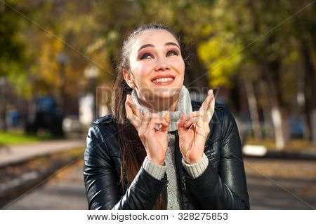 Body language and emotions concept. Young beautiful satisfied woman beggs God to help her, keeps fingers crossed, wishes good luck