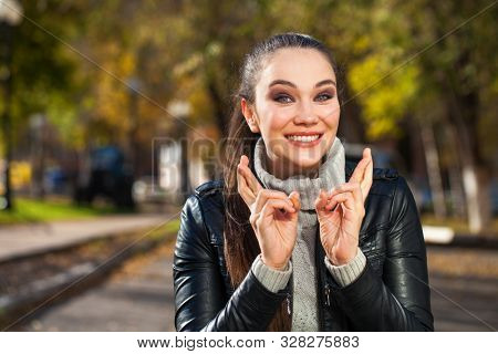 Body language and emotions concept. Young beautiful satisfied woman beggs God to help her, keeps fingers crossed, wishes good luck