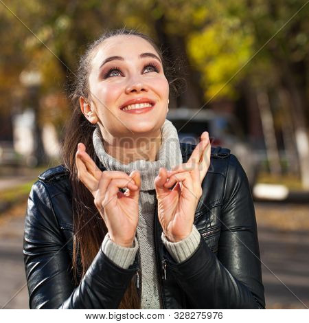 Body language and emotions concept. Young beautiful satisfied woman beggs God to help her, keeps fingers crossed, wishes good luck