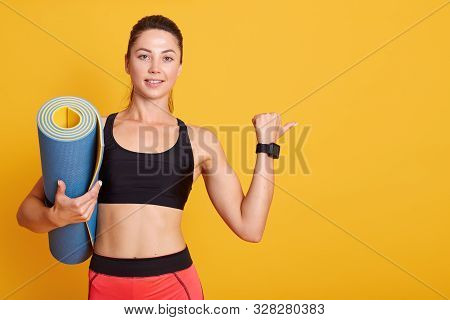 Close Up Portrait Of Dark Haired Woman Raises Arm, Shows Muscles After Training, Holds Blue Karemat,