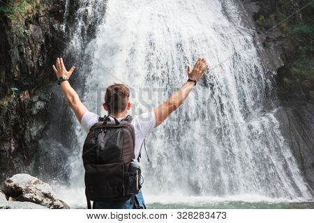 Man at Korbu Waterfall on the Lake Teletskoye in autumn Altai Mountains.