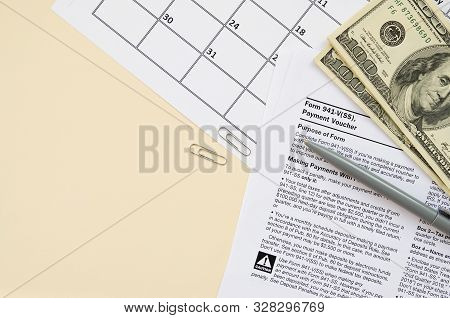 Irs Form 941-v Payment Voucher Blank Lies With Pen And Many Hundred Dollar Bills On Calendar Page