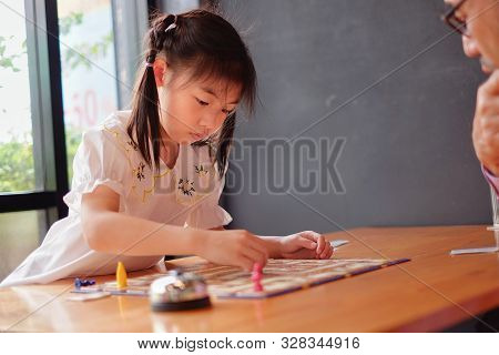 An Attractive Asian Preschool Girl Learning To Play Board Games With Her Grandfather