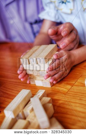 An Grandfather Is Teaching His Granddaughter To Play A Block Wood Tower Game.