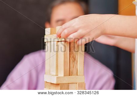 An Grandfather Is Teaching His Granddaughter To Play A Block Wood Tower Game.