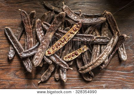 Carob pods and carob beans on the wooden table.