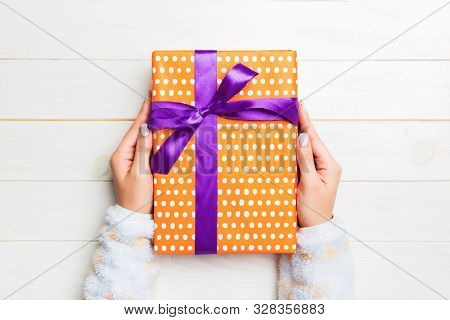 Top View Woman Hands Holding Present Box With Colored Bow On White Wooden Background With Copy Space