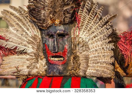 Mummers perform rituals to scare evil spirits at Surva festival at Pernik in Bulgaria. The people with the masks are called Kuker (kukeri). Wood mask with feathers and red mouth.