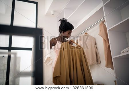 Curly Dark-haired Woman Choosing Cardigan In The Morning