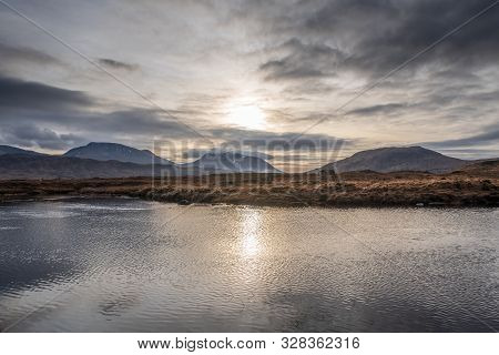 Wetlands And Wintery Grass Fields As The Sun Starts To Set Over The Black Mount Mountain Range On A 