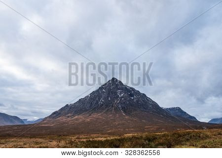 Wintery Brown Grass Fields Overlooks Buachaille Etive Mòr Mountain On A Cloudy Day In The Scottish H