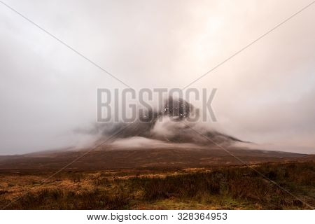 Wintery Brown Grass Fields Overlooks Buachaille Etive Mòr Mountain Covered In Clouds In The Scottish