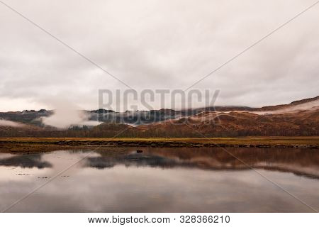 Calm Waters At Loch Eil With A View Of The Wintery And Brown Scottish Highlands On Cloudy Day.