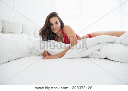 Young Attractive Woman In Red Sexy Underwear Lying In Bed In Bright Bedroom Smiling