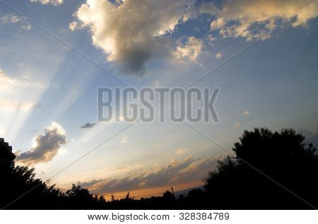 Sun Rays Unlighting A Blue Sky With Some Clouds