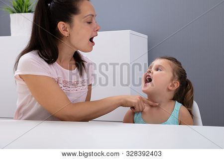 An Attractive Female Speech Therapist Helps The Girl How To Pronounce The Sounds In Office