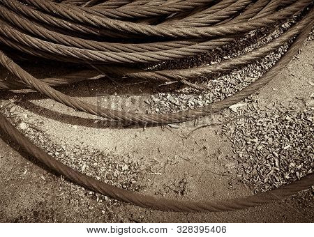 Old Rusty Strong Cable Rolled Into The Bay. The Rings Of Iros Are Located On The Ground, The Yard Of