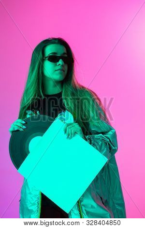 The Girl With The Vinyl Record. Colored Background And Neon Light. Modern Clothes. Music Poster. Ret