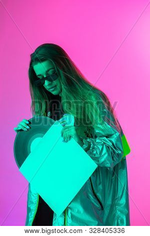 The Girl With The Vinyl Record. Colored Background And Neon Light. Modern Clothes. Music Poster. Ret