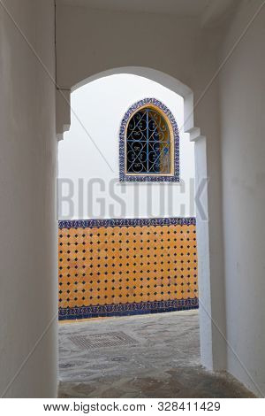 Narrow old street with a mosaic decorated house in the medina of Asilah, Morocco