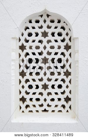 Traditional Moroccan white window protected with a design shutter in Asilah, Morocco