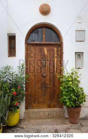 Old wooden decorated door with knocker in the shape of a hand in Asilah, Morocco