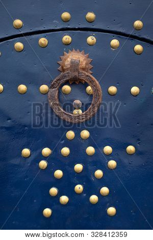 Simple old metal knocker as a detail on a blue painted wooden door in Assilah, Morocco