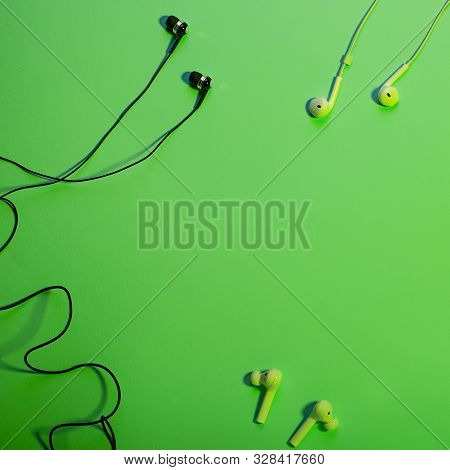 Headphones Of Different Types Flat Lay On Green Color Background, Copy Space. Black In Ear Headphone