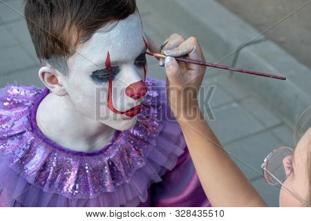 Body Painting Or Street Makeup. Female Hand Holds A Brush And Paints The Face Of A Teenager. The Ima