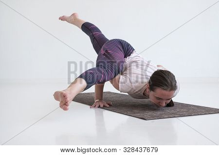 Practicing Yoga, Doing Eka Pada Koundinyasana 2, Arm Balance Twisted Pose.