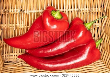 Group Of Three Whole Sweet Red Bell Pepper With Braided Rattan Behind