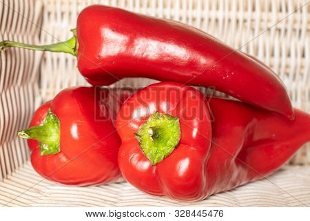 Group Of Three Whole Sweet Red Bell Pepper With Braided Rattan Behind