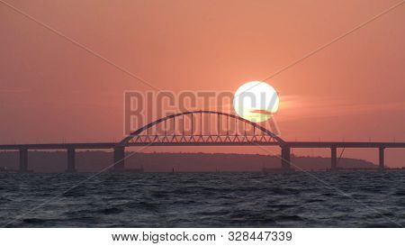Stunning View Of The Beautiful Sunset Over The Big River And The Bridge, Time Lapse Effect. Shot. Br