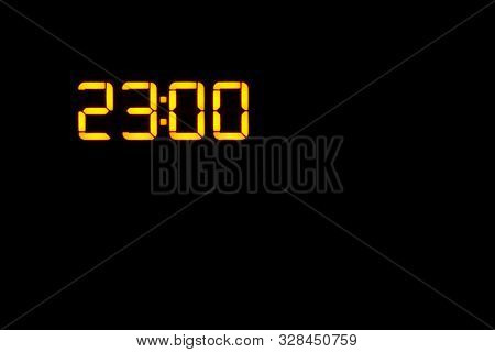 Electronic Clock Showing The Time 23:00 On The Display Orange Leds On A Black Background. Copy Space