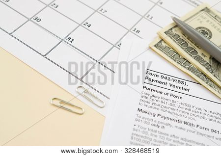 Irs Form 941-v Payment Voucher Blank Lies With Pen And Many Hundred Dollar Bills On Calendar Page