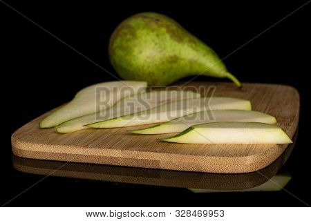 Group Of One Whole Five Slices Of Fresh Green Pear On Bamboo Cutting Board Isolated On Black Glass