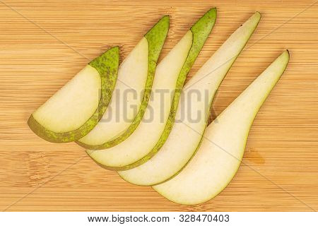Group Of Five Slices Of Fresh Green Pear Flatlay On Light Wood